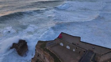 Nazare Deniz Feneri. Portekiz 'deki en büyük dalgalar. Büyük Naziler Dalgaları, Günbatımı Zamanı Hava Aracı Atışı. Yüksek kalite 4k görüntü