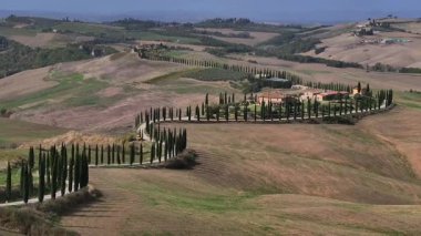 Tipik Toskana hava manzarası. İtalyan Tepe Bölgesi 'nin üzerinde havadan çekilmiş bir video. Bir günde selvi ile dolambaçlı bir yol. Yüksek kalite 4k görüntü