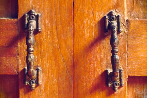 The vintage door handle on an old wooden door background and lighting and shadow in the morning. Closeup and copy space on the centred. The concept of art and architecture in vintage style.