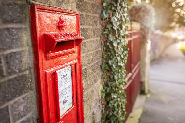 SWANSEA, WALES, UK - FEBRUARY 25, 2021: Classic British red Royal Mail mailbox for letters on a wall in a street in Wales, United Kingdom