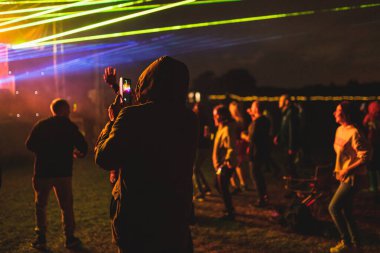 Birleşik Krallık 'ın Birmingham kenti yakınlarında bir açık hava elektronik müzik festivali var. Telefonuyla fotoğraf çeken bir adam..