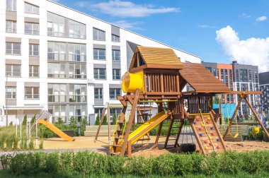 Konut binasının yanında salıncakları, slaytları ve tırmanma duvarları olan modern ahşap oyun alanı