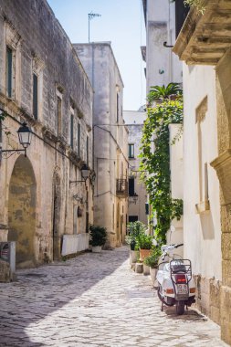 İtalya, Otranto 'da eski bir kasaba, Apulia dar sokağı beyaz bir scooter park etmiş.