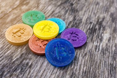 Ahşap masanın üzerinde gökkuşağı renklerinde renkli Bitcoin paralar