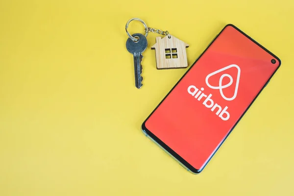 Téléphone avec logo Airbnb, clé avec porte-clés maison — Photo