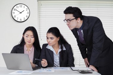 İş adamları ile saat ofiste dizüstü bilgisayar kullanmak