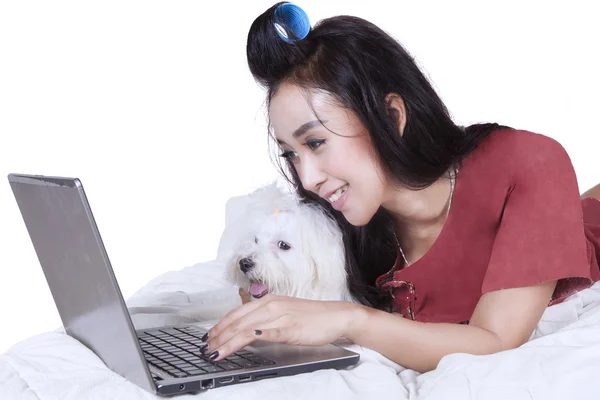 Schöne Frau mit Hund benutzt Laptop auf dem Bett — Stockfoto
