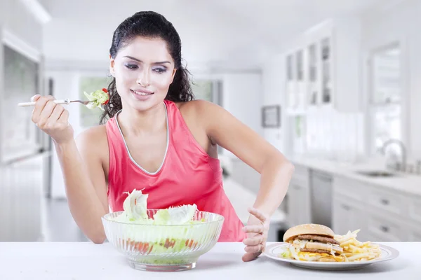 Model lehnt Cheeseburger ab und isst Salat — Stockfoto
