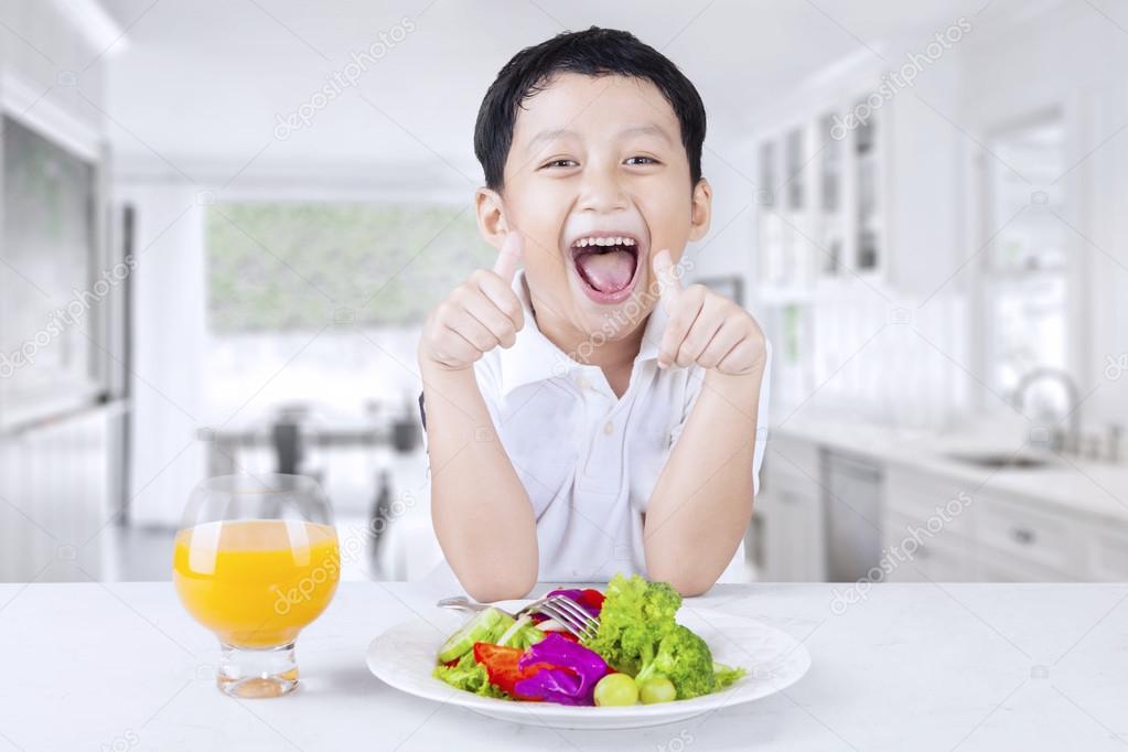 Male kid with fresh salad and juice