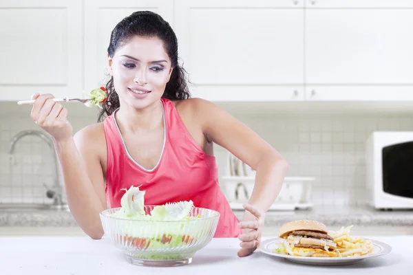 Femme mange de la salade et refuse cheeseburger — Photo