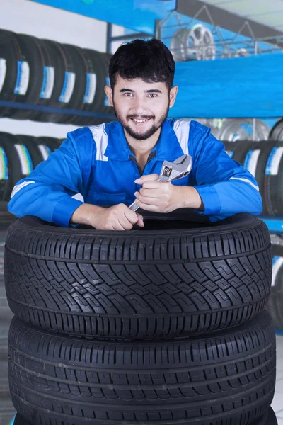 Mladá mechanik s úsměvem v úložišti pneumatiky — Stock fotografie