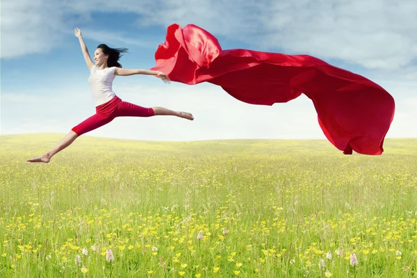 Balletdanseres springt met stof op veld — Stockfoto