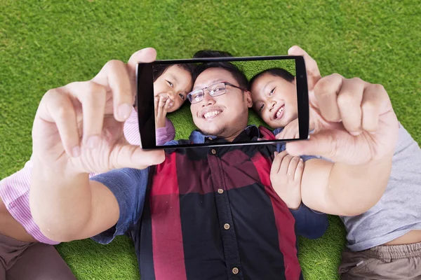 Bonito crianças tomando selfie com o pai no campo — Fotografia de Stock