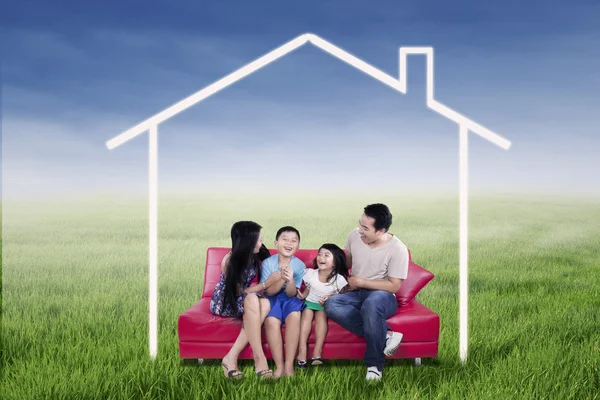 Família excitada sentada sob casa dos sonhos — Fotografia de Stock