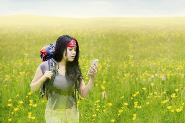 Mochilera femenina con smartphone en la naturaleza — Foto de Stock