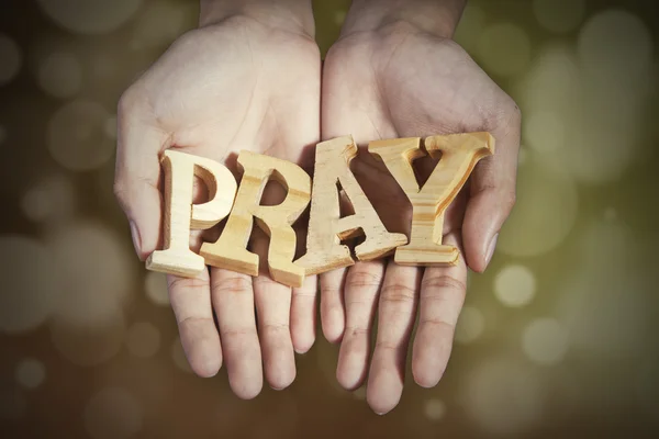 Ruce se slovo modlit v pozadí bokeh — Stock fotografie