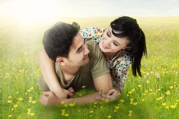 Casal feliz deitado na grama na primavera — Fotografia de Stock