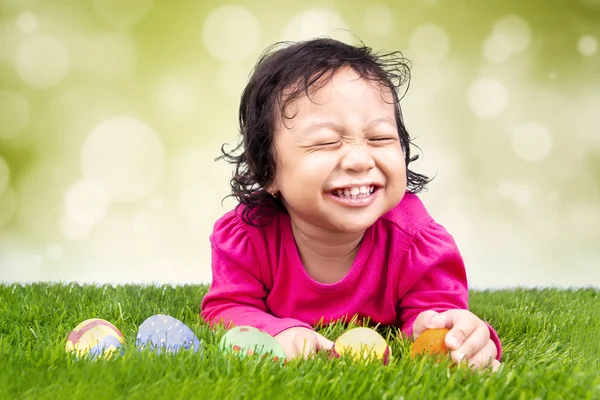 Liten flicka att hitta påsk ägg på gräs — Stockfoto
