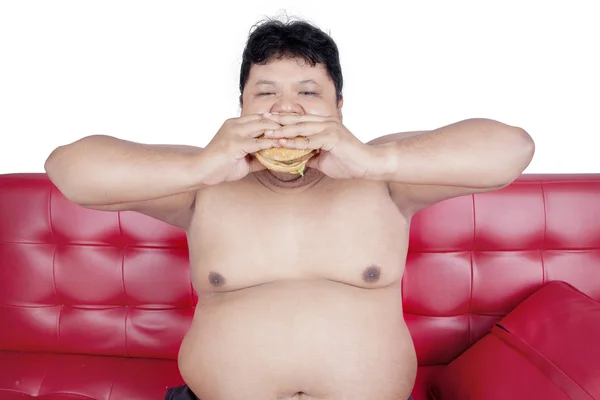 Overweight man eats burger with two hands — Stock Photo, Image