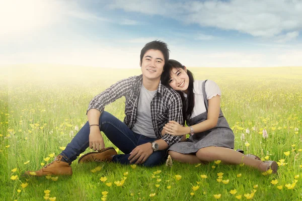 Romantický pár sedí u pole v jarní — Stock fotografie