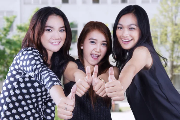 Tre kvinnliga studenter visar tummen upp — Stockfoto