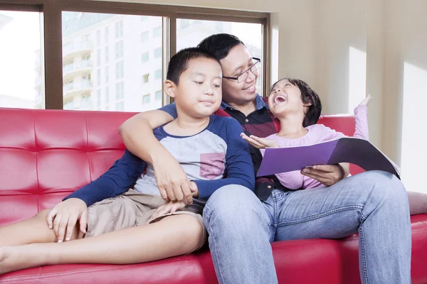 Dos niños y su padre leyeron un libro —  Fotos de Stock