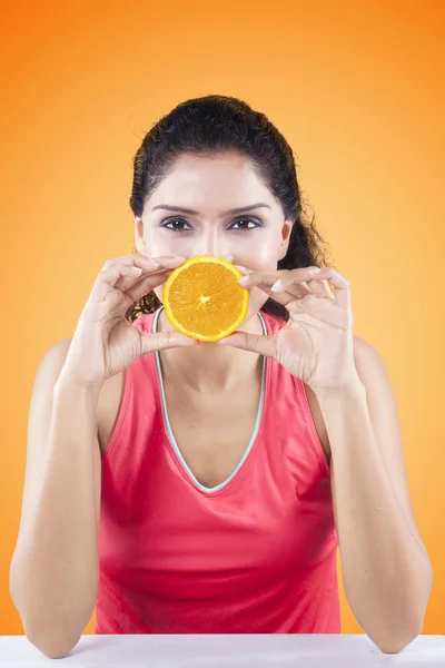 Vrouw die betrekking hebben op haar mond met oranje Fruit — Stockfoto