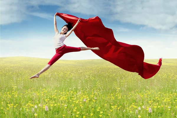 Woman holds fabric and leaps on meadow — Stock Photo, Image