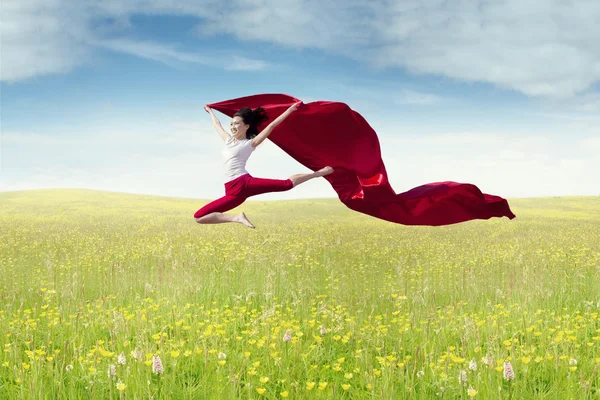 Vrouw springt met rode stof — Stockfoto