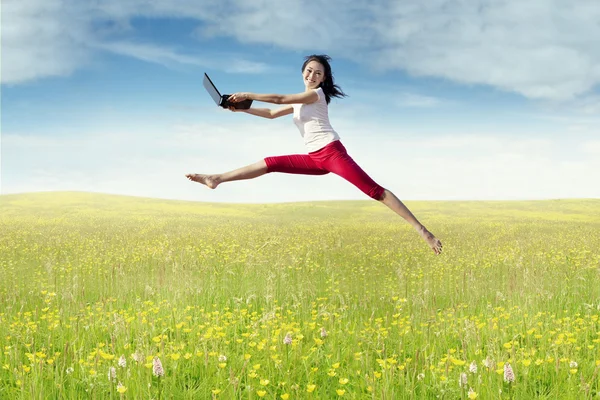 Woman with laptop leaps in the nature — Stock Photo, Image