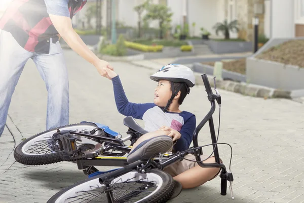 Criança recebe ajuda de seu pai depois de cair de bicicleta — Fotografia de Stock