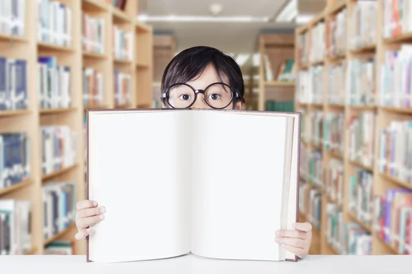Kid segura livro em branco na biblioteca — Fotografia de Stock