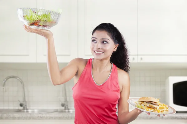 Pretty model comparing foods in kitchen — Stock Photo, Image