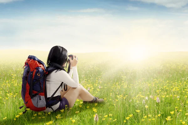 Hiker with bag taking pictures on meadow — Stock Photo, Image