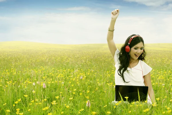 Mujer escuchar música con portátil en el campo — Foto de Stock