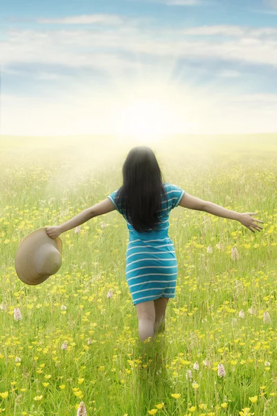 Vrouw met uitgestrekte handen loopt op veld — Stockfoto