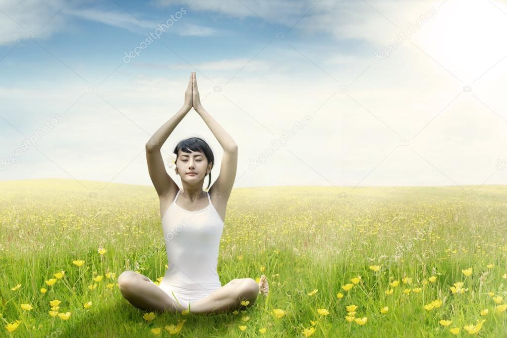 Woman meditating on grass at field