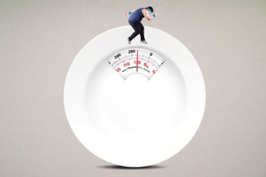 Obez adam bir tabak şeklinde ölçek üzerinde çalışır