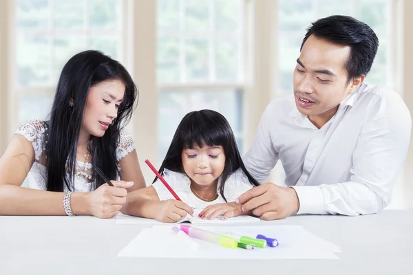 Hermosa niña haciendo el trabajo escolar con los padres — Foto de Stock