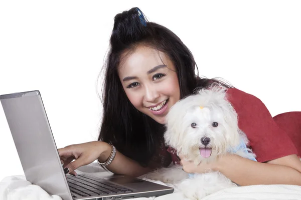 Fröhliches Model mit Hund und Laptop auf dem Bett — Stockfoto