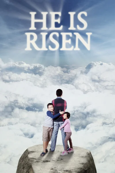 Children with their dad looking at text he is risen — Stock Photo, Image