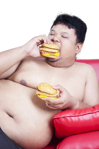 Pessoa com excesso de peso come dois cheeseburgers — Fotografia de Stock