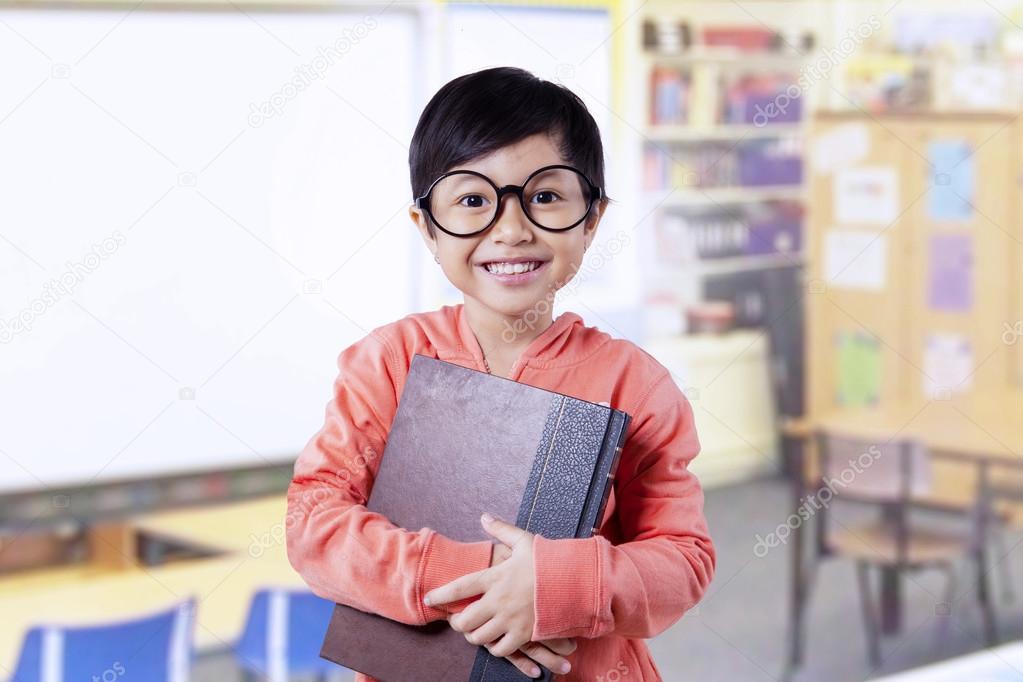 Beautiful little student holds books in class