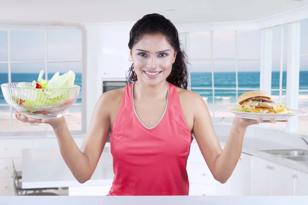 Femme indienne compare salade et cheeseburger — Photo