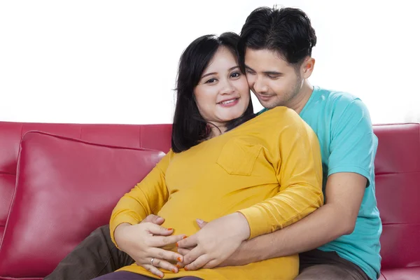 Беременная женщина и ее муж сидят на диване — стоковое фото