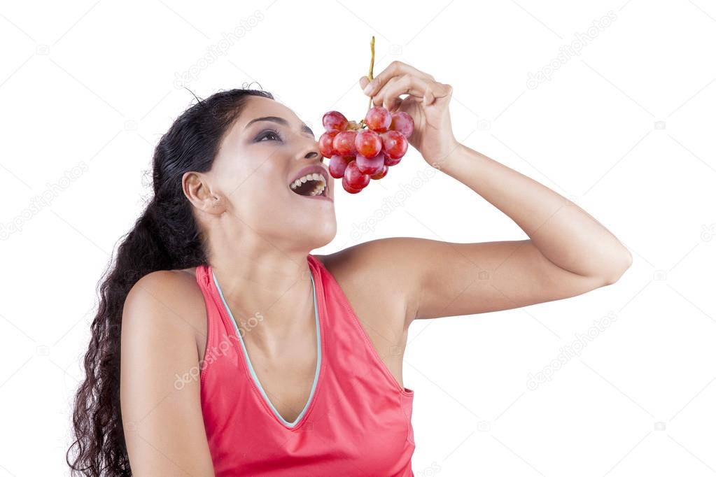 Indian woman eating red grapes Stock Photo by ©realinemedia 103489236
