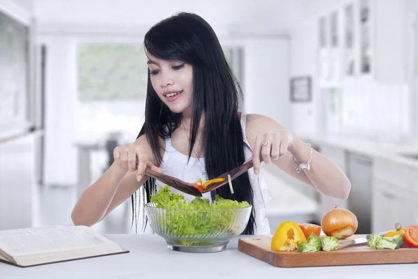 Mujer joven cocina ensalada en casa — Foto de Stock