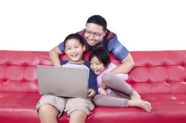 Mutlu çocuk ve baba kanepede dizüstü bilgisayar kullanmak