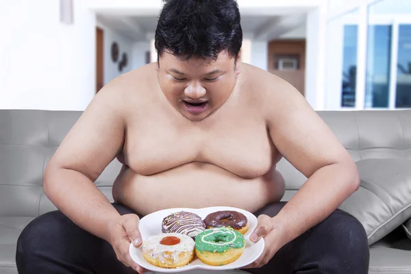 Fat man met een plaat van donuts — Stockfoto