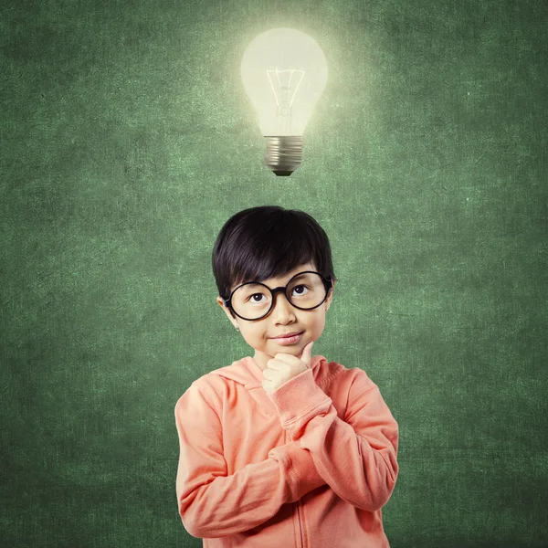 Child in thinking poses while looking at lamp — Stock Photo, Image